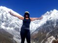 a woman standing on top of a mountain with her arms outstretched
