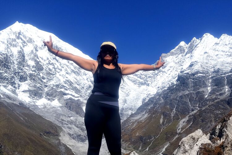 a woman standing on top of a mountain with her arms outstretched